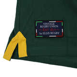 Close-up of a green fabric featuring a yellow corner detail and a patch reading “Vintage Rugby Union Est 1871 by Ellis Rugby,” bordered in red, green, white, and blue—capturing the classic look of the Ellis Rugby South Africa Rugby Polo 1924 by Ellis Rugby, inspired by iconic Springbok rugby heritage.