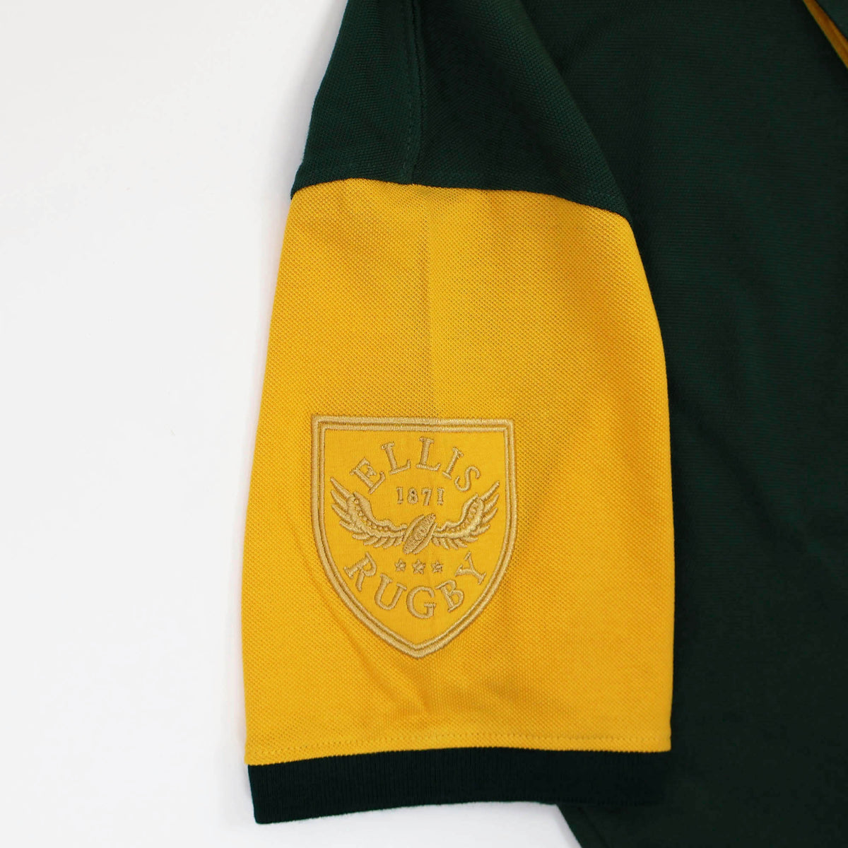 The South Africa Rugby Polo 1924 by Ellis Rugby is a yellow and green short-sleeve shirt, featuring an embroidered patch on the sleeve with an eagle graphic and the words “ELLIS 1871 RUGBY,” inspired by classic Ellis Rugby and South Africa rugby polo designs.