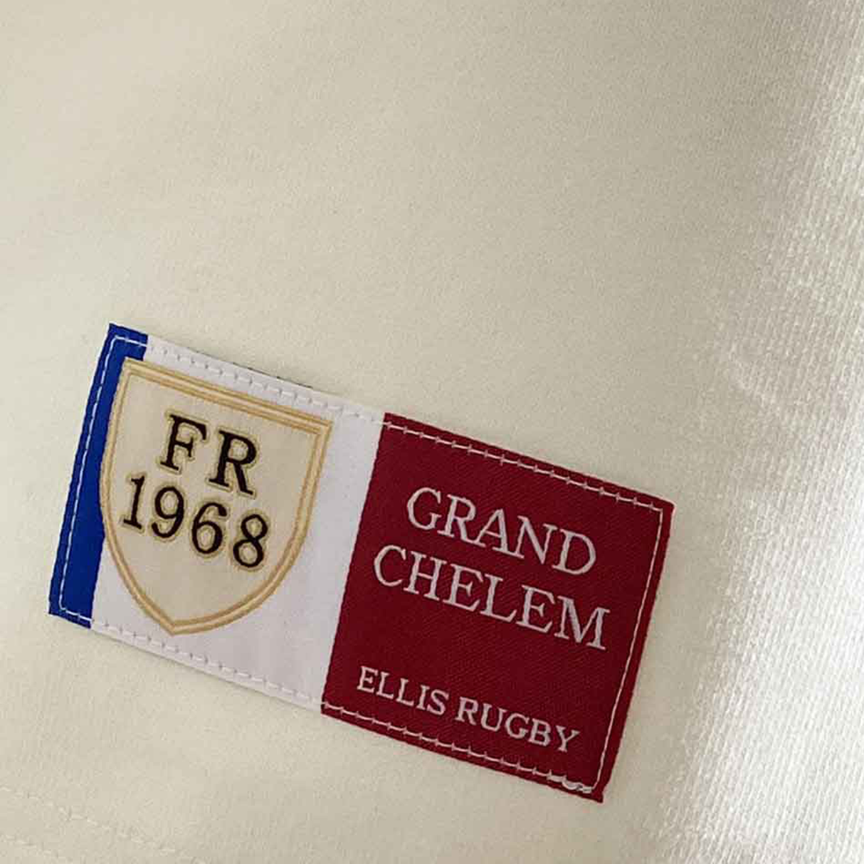 The France 1968 Grand Slam Classic Rugby Shirt by Ellis Rugby features a tricolor embroidered patch with "France 1968" and "GRAND CHELEM ELLIS RUGBY," attached to cream fabric.