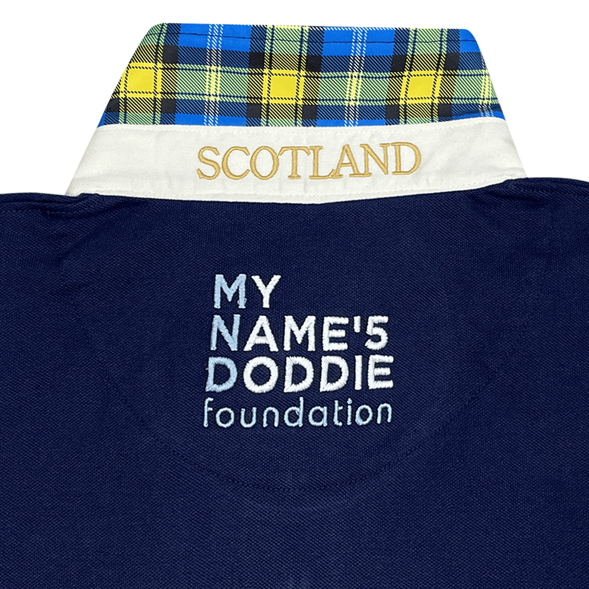 Close-up of a navy fabric with "MY NAME'5 DODDIE foundation" text and a collar featuring "SCOTLAND" embroidery with tartan trim, reflecting the Ellis Rugby Doddie Weir Classic Jersey's blue, yellow, and black plaid design.