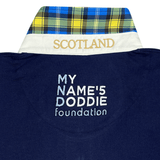 Close-up of a navy fabric with "MY NAME'5 DODDIE foundation" text and a collar featuring "SCOTLAND" embroidery with tartan trim, reflecting the Ellis Rugby Doddie Weir Classic Jersey's blue, yellow, and black plaid design.