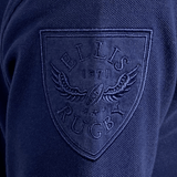 Close-up of the Ellis Rugby Doddie Weir Classic Jersey, showcasing navy blue fabric with an embroidered "Ellis Rugby 1871" shield logo featuring a rugby ball and wing design, and accented by a subtle tartan trim.