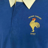 Close-up of the Ellis Rugby France Rugby 21 Club Collection 1997 Rugger in blue, featuring a yellow collar, an embroidered rooster, and the text "Grand Chelem 1997" on the left chest area—a perfect example of a Vintage rugby shirt by Ellis Rugby.