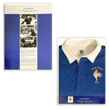 The Ellis Rugby France Rugby 21 Club Collection 1997 Rugger, a vintage shirt with a blue body, white collar, and "Grand Chelem 1997" emblem, is prominently displayed. Beside it, a framed informational panel showcases black and white photos and text about rugby's history.