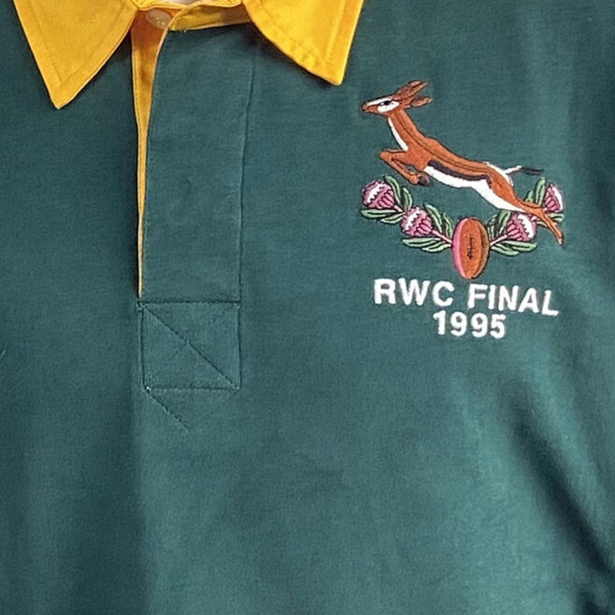 The Ellis Rugby Springbok 1995 Vintage Long Sleeve Rugby Shirt honors South Africa's rugby history with a green design, yellow collar, pink flowers, embroidered springbok, and "RWC Final 1995" text celebrating their iconic win.