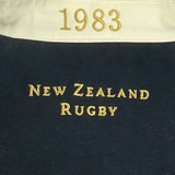 Close-up of the Ellis Rugby All Blacks 1983 Classic Rugby Shirt, featuring "1983" on the collar with "New Zealand Rugby" beautifully embroidered in gold on black fabric, reminiscent of an All Blacks shirt.