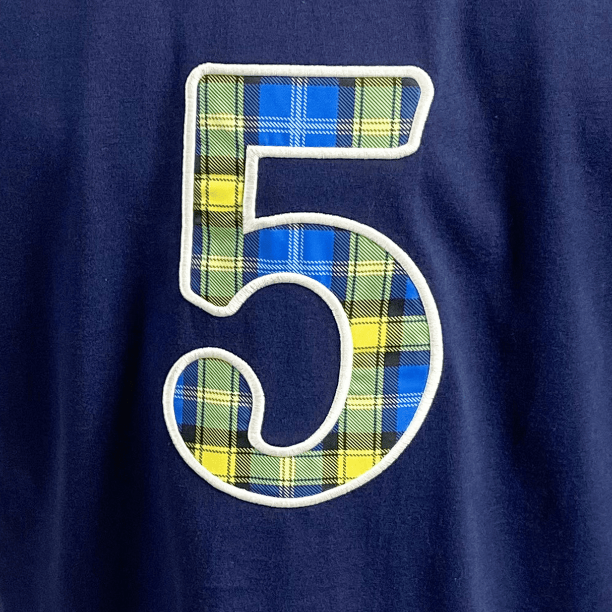 The Ellis Rugby Doddie Weir T-Shirt features a number 5 in a plaid design of blue, yellow, and green on a dark blue background, evoking the vintage Scotland crest.