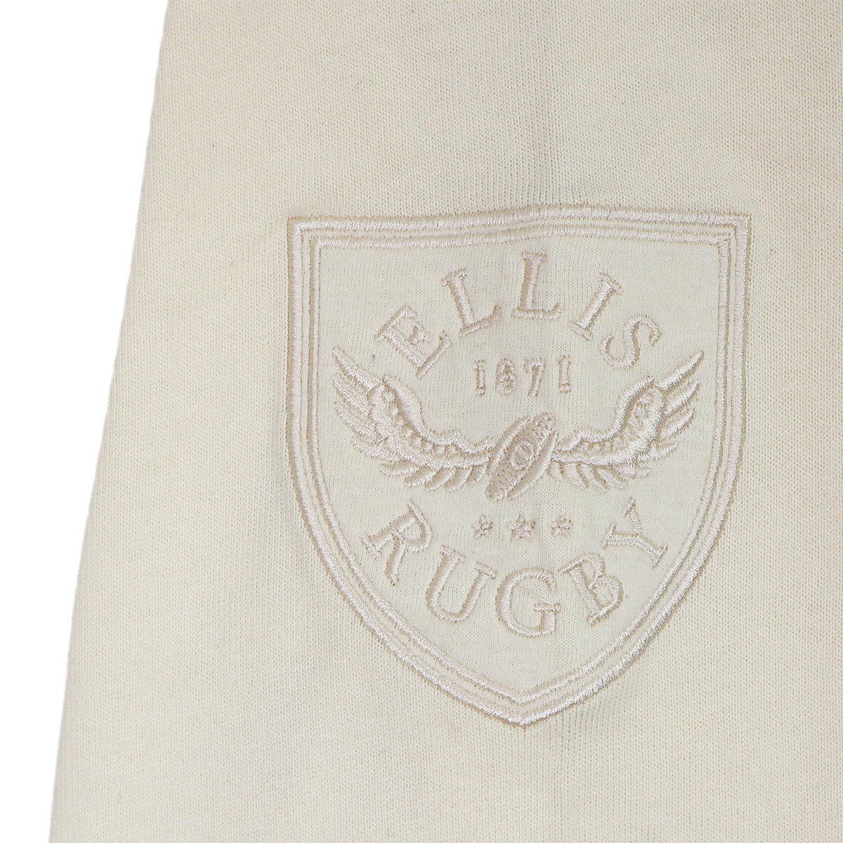 A cream fabric patch with a shield featuring the “ELLIS RUGBY” text, a winged rugby ball, and the year 1871—all embroidered in white thread—this timeless accessory by Ellis Rugby is inspired by the legacy of the England Rugby 1991 Shirt 1992 Grand Slam.