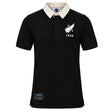 The New Zealand Rugby 1924 Polo by Ellis Rugby is a black, short-sleeved polo shirt featuring a contrasting white collar, a white fern and “1924” on the chest, and a rectangular patch near the hem—a subtle nod to New Zealand Rugby heritage.