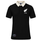The New Zealand Rugby 1924 Polo by Ellis Rugby is a black, short-sleeved polo shirt featuring a contrasting white collar, a white fern and “1924” on the chest, and a rectangular patch near the hem—a subtle nod to New Zealand Rugby heritage.