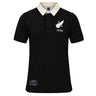 The New Zealand Rugby 1924 Polo by Ellis Rugby is a black, short-sleeved polo shirt featuring a contrasting white collar, a white fern and “1924” on the chest, and a rectangular patch near the hem—a subtle nod to New Zealand Rugby heritage.