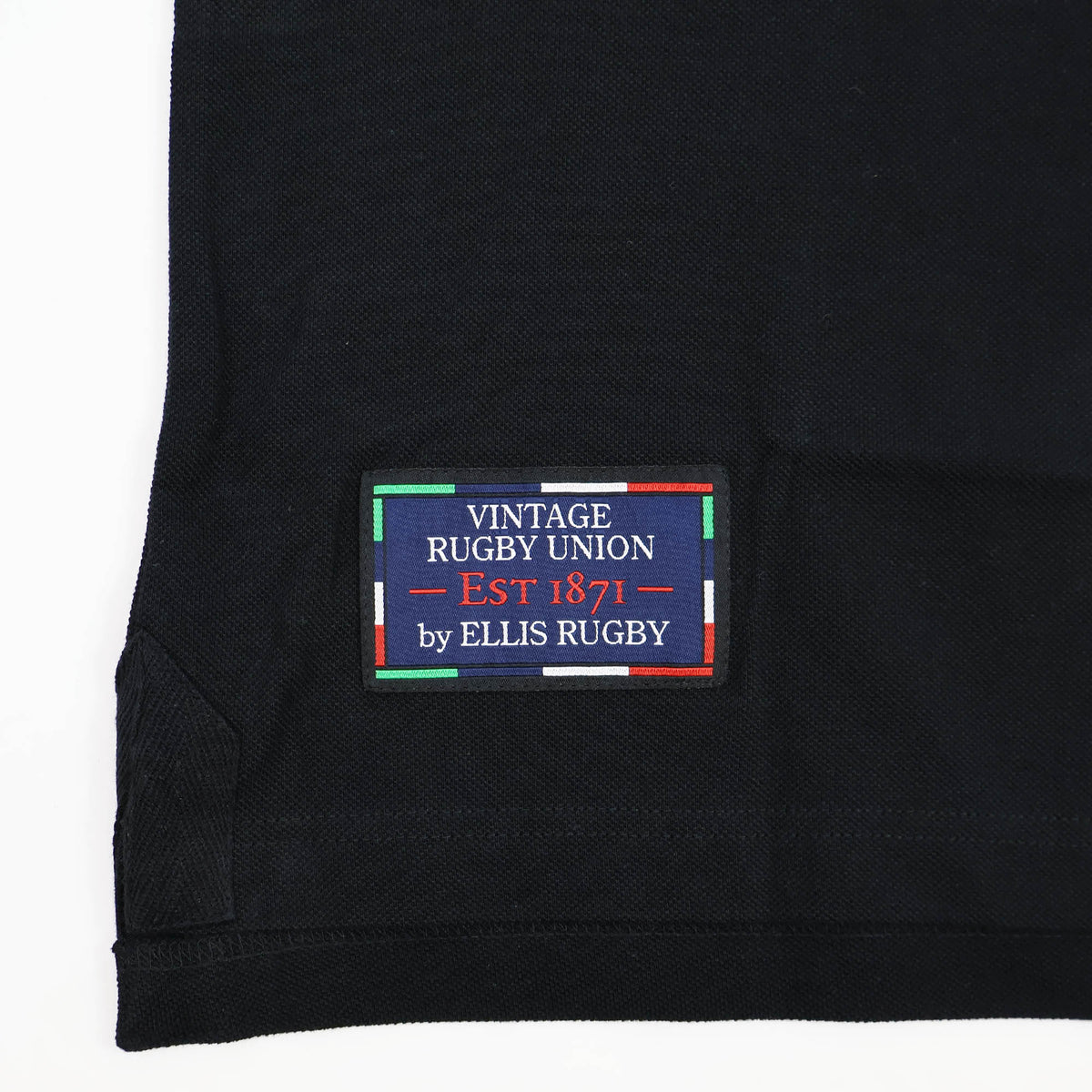 A black fabric featuring a stitched label that reads “Vintage Rugby Union EST 1871 by Ellis Rugby,” bordered by colorful stripes, pays homage to rugby heritage—an iconic style inspired by the classic traditions of New Zealand Rugby, as seen in the New Zealand Rugby 1924 Polo by Ellis Rugby.