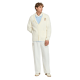 A man faces forward in the adidas France FFR 120 Year Cardigan—honoring 120 years of French rugby—styled with a light blue shirt, white pants, and beige shoes against a plain white background.