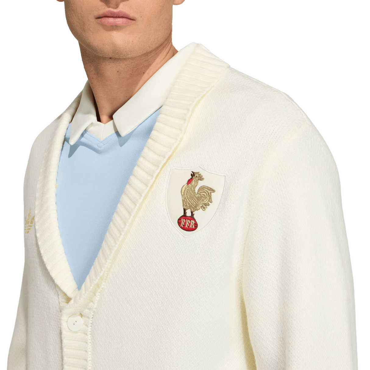 A person wearing the adidas France FFR 120 Year Cardigan, featuring a ribbed collar and rooster crest patch, over a light blue collared shirt—celebrating 120 years of French rugby heritage.