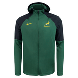 The Springboks Full Zip Training Hoodie by Nike in green and black comes with a hood and features a yellow swoosh logo on the left chest. On the right chest, you'll find the springbok emblem accompanied by "SPRINGBOKS." This moisture-wicking jacket keeps you comfortable and stylish.