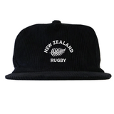 The EMB Weld Nations of Rugby New Zealand Corduroy Field Trip Cap is a vintage-style black hat featuring "NEW ZEALAND RUGBY" and a white fern embroidered on the front.