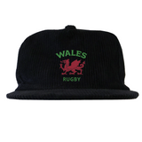 The EMB Weld Nations of Rugby Wales Corduroy Field Trip Cap is a black corduroy cap with a red Welsh dragon and "WALES RUGBY" embroidered in green and red—perfect for Wales Rugby fans.