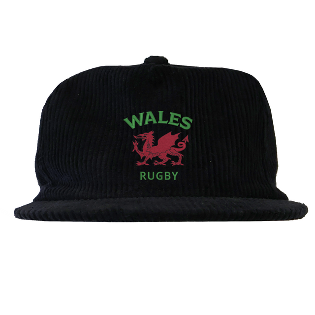 The EMB Weld Nations of Rugby Wales Corduroy Field Trip Cap is a black corduroy cap with a red Welsh dragon and "WALES RUGBY" embroidered in green and red—perfect for Wales Rugby fans.
