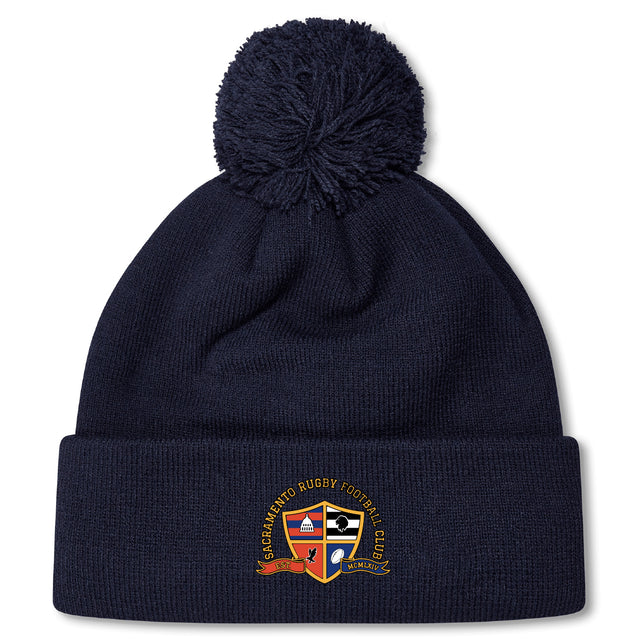 Stay warm on chilly days with the Sacramento Rugby Football Club Pom Pom Beanie by EMB Canterbury, featuring navy blue fleece lining, a pom-pom top, and the SRCF crest embroidered on the front.
