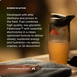 A shaker bottle with an orange drink sits on a table next to text about Momentous Fuel 10-Travel Packs, a carb electrolyte formula by Momentous designed to deliver sustained energy and hydration for endurance exercise.
