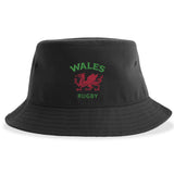 Introducing the Nations of Rugby Wales Rugby Sustainable Bucket Hat by EMB S&S Activewear—crafted from recycled polyester, this black bucket hat showcases "WALES RUGBY" text and an embroidered red dragon emblem on the front, making it a perfect eco-friendly choice for passionate fans.