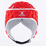 The XP 250 Rugby Headguard by Gilbert is a red headguard featuring a honeycomb pattern and hex padding for sports protection. It includes an adjustable strap and has a white interior.