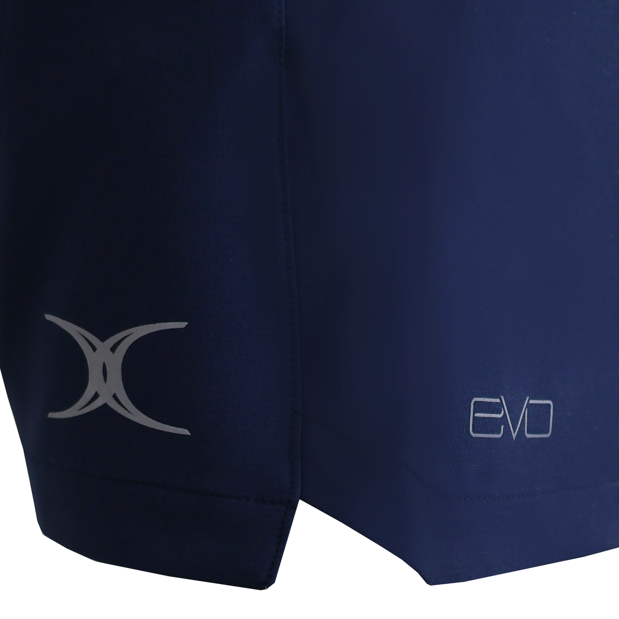 Close-up of the lower part of dark blue Gilbert Evo Shorts made from lightweight, breathable fabric, with two logos—an abstract design on the left and "EVO" on the right—ideal for today’s rugby players.