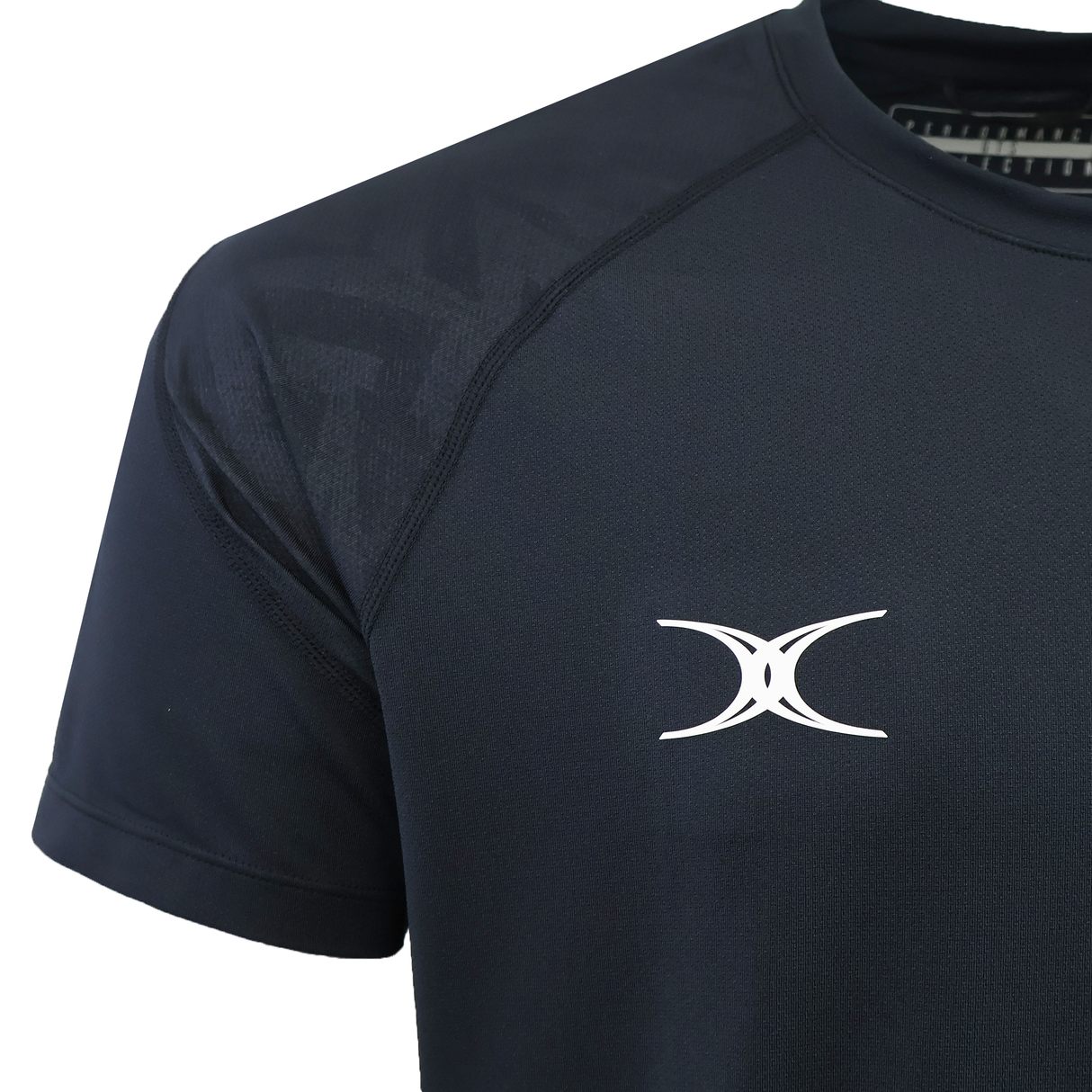 Close-up of the black Gilbert GTS Training Tee by Gilbert, featuring a white abstract logo on the left chest and moisture wicking fabric.