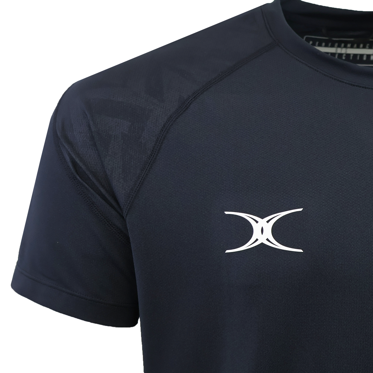 Close-up of the Gilbert GTS Training Tee by Gilbert in dark navy, featuring a white abstract logo on the chest. Designed for peak performance and moisture wicking, showing upper torso and partial sleeve.