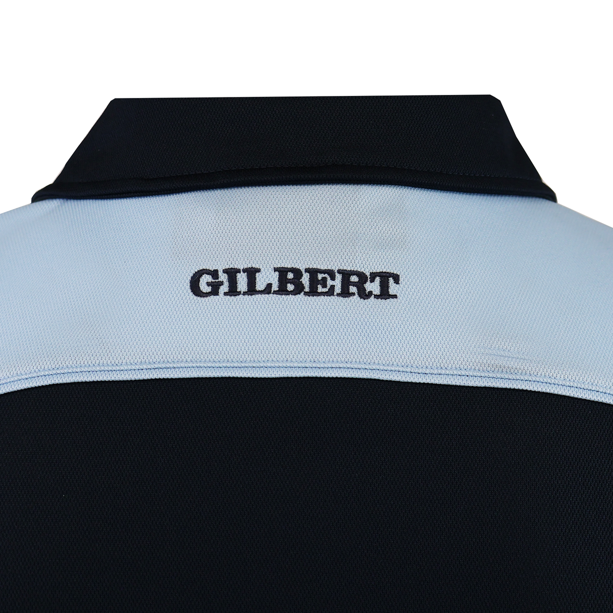 Close-up of the Gilbert Photon II Polo's back, showing "GILBERT" embroidered in black on a light blue panel. This polo features lightweight, moisture-wicking fabric to keep you cool and comfortable all day.