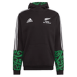 Introducing the Maori All Blacks Performance Hoodie by adidas, a striking black rugby hoodie flaunting "Māori All Blacks" text and a silver fern emblem. This performance piece proudly displays the iconic Adidas logo, complemented by white stripes and vibrant green Māori patterns on its sleeves and hood, perfectly merging style with athletic heritage.