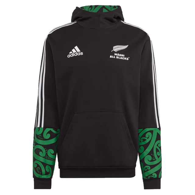 Introducing the Maori All Blacks Performance Hoodie by adidas, a striking black rugby hoodie flaunting "Māori All Blacks" text and a silver fern emblem. This performance piece proudly displays the iconic Adidas logo, complemented by white stripes and vibrant green Māori patterns on its sleeves and hood, perfectly merging style with athletic heritage.