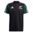 Maori All Blacks Performance Polo by adidas showcases a striking black design with the classic white Adidas logo and "Māori All Blacks" text, accompanied by a fern emblem on the front. The shoulders are enhanced with a green Māori pattern, while three white stripes adorn the sleeves. It also features moisture-wicking AEROREADY technology for added comfort.