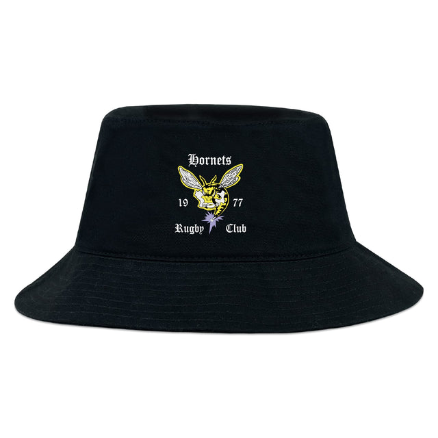 The Hornets Rugby Club Crusher Bucket Cap by EMB S&S Activewear is a black cotton twill hat with sun protection, featuring an embroidered yellow hornet and white "Hornets Rugby Club 1977" on the front.