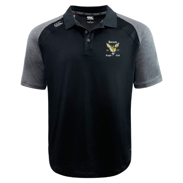 The Hornets Rugby Club Elite Polo by EMB Canterbury is a black and gray lightweight polo with a collar, button placket, Vapodri fabric, and an embroidered "Hornets Rugby Club 1977" logo on the left chest.
