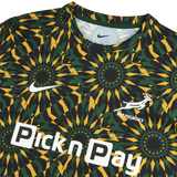 The Nike Springboks 26/27 Pre-Match Top showcases a geometric green, yellow, and black design with the Nike logo, Springboks emblem, and Pick n Pay sponsor—ideal as a rugby shirt or pre-match top.