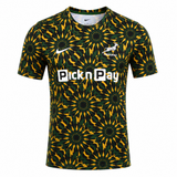 The Nike Springboks 26/27 Pre-Match Top is a short-sleeve rugby jersey with a green, yellow, and black geometric design—ideal as a Springboks pre-match shirt or as official Nike rugby gear.