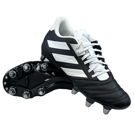 The adidas Kakari Elite SG cleats in Core Black, Zero Metallic, and Silver Metallic feature metal studs, making them an ideal choice for soft ground rugby. One shoe stands upright while the other is on its side, prepared for action.