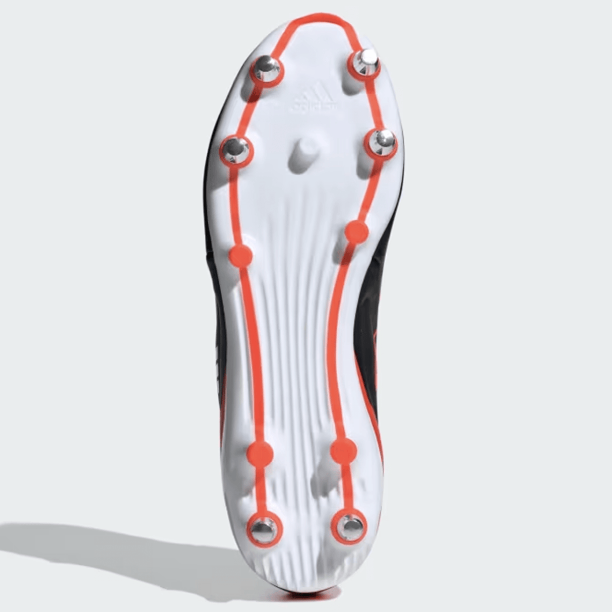 The bottom view of the adidas RS15 Elite SG 24 Rugby Cleat (Core Black/Core Black/Solar Red) showcases its metal spikes and a white sole accented with an orange band outlining the spike arrangement.