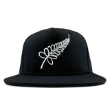 An All Blacks Snapback Cap by adidas, featuring a black design with a white embroidered fern on the front, showcasing New Zealand pride.