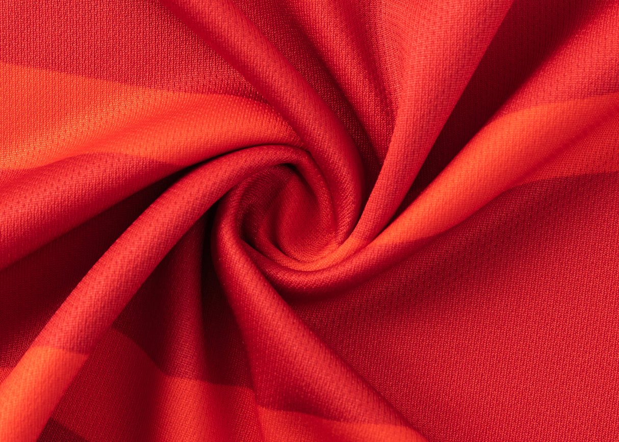 Close-up of the Dolphins NRL 25/26 Replica Home Jersey by Classic Sportswear, featuring vibrant red fabric with swirling folds, textured surface, and various shades of red reminiscent of classic sportswear design.