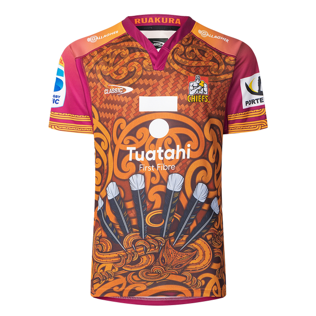 The Gallagher Chiefs Super Rugby Replica Training Jersey 25/26 by Classic Sportswear features brown and orange patterns, a "Chiefs" logo, sponsor logos, stylized feathers, and tribal designs—ideal for fans who love tradition and style.