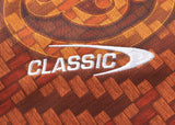 Close-up of an orange textile resembling the Gallagher Chiefs Super Rugby Replica Training Jersey 25/26 by Classic Sportswear, with "CLASSIC" and a white arc design. The background highlights abstract orange and brown geometric patterns reflecting the dynamic spirit of the Gallagher Chiefs.