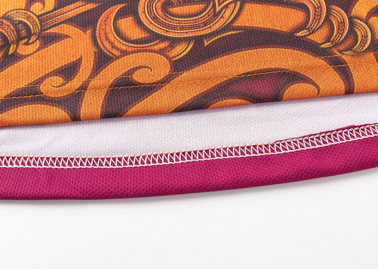 A close-up of the Gallagher Chiefs Super Rugby Replica Training Jersey 25/26 by Classic Sportswear showcases the intricate orange and brown pattern with a red border, highlighted against a white background, reflecting team spirit and craftsmanship.