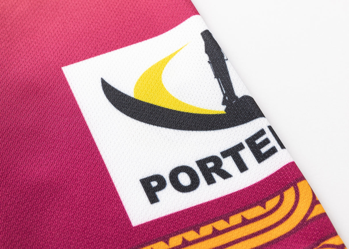 Close-up of the Gallagher Chiefs Super Rugby Replica Training Jersey 25/26 by Classic Sportswear fabric, featuring a stylized black and yellow logo with "PORTER" in black text. This maroon jersey captures the spirit and fervor of Super Rugby.