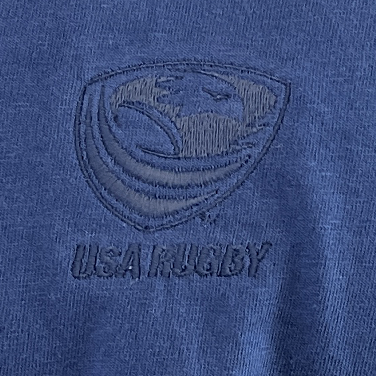 Close-up of a navy USA Rugby Elevated Tonal Comfort Tee by EMB Alpha Broder, ideal for Eagles fans, featuring an embroidered USA Rugby logo with a stylized rugby ball and eagle in a shield design.