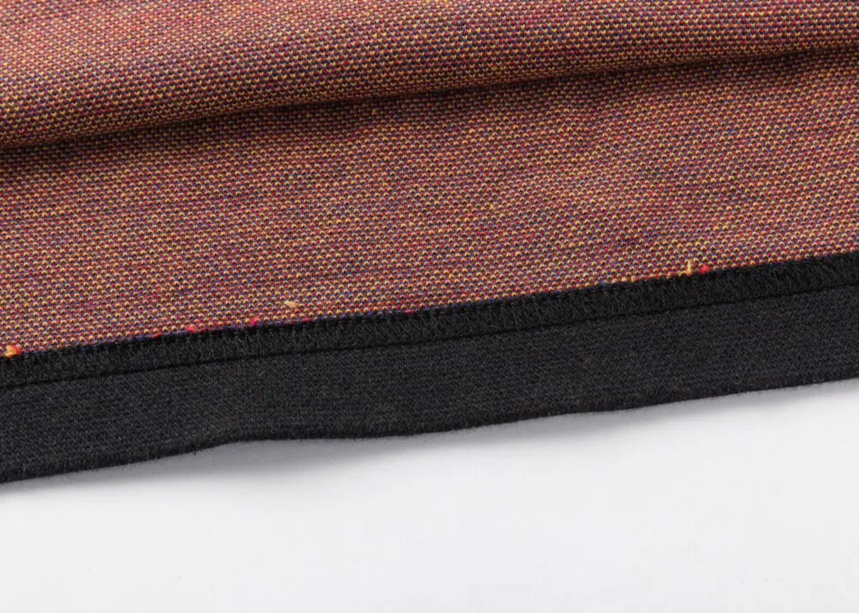 Close-up of a folded fabric with a retro jersey vibe, featuring a brown weave pattern and black edge trim resembling the spirited style of Classic Sportswear's Limited Edition Gallagher Chiefs Super Rugby 25/26 Retro Jersey, resting on a flat surface.