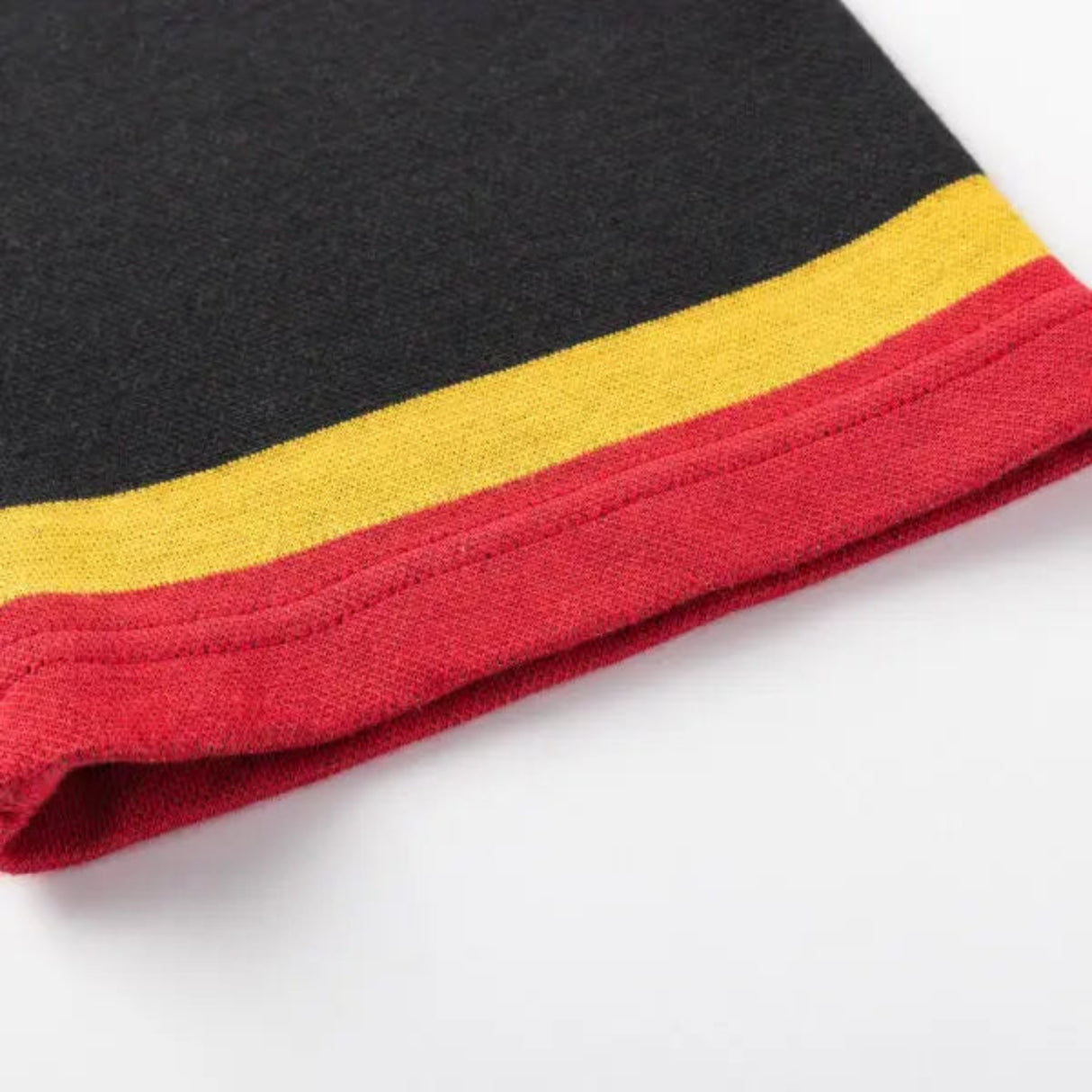 Close-up of a Gallagher Chiefs Super Rugby 25/26 Retro Jersey hem by Classic Sportswear, featuring black, yellow, and red horizontal stripes reminiscent of classic sportswear.