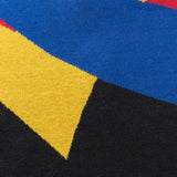 Close-up of a fabric featuring a geometric pattern in blue, yellow, black, and red sections, akin to the Limited Edition Gallagher Chiefs Super Rugby 25/26 Retro Jersey by Classic Sportswear.