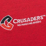 Close-up of a red Limited Edition Crusaders Super Rugby 25/26 Retro Jersey by Classic Sportswear, embroidered with "Crusaders" and "Mā pango mā whero" in white, featuring a stylized logo in black and red, this classic piece proudly connects to Super Rugby's heritage.